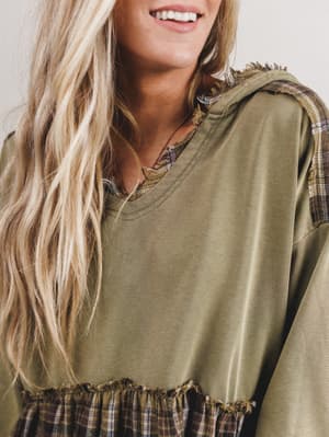 Person wearing a green oversized shirt with plaid accents