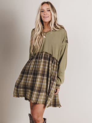 Woman wearing a green dress with plaid skirt on a plain background