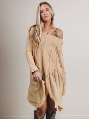 Woman wearing a beige long-sleeve dress with a plain background