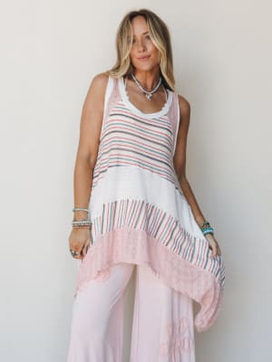 A breezy, layered look featuring a striped knit tunic with an asymmetric handkerchief hem over soft pink wide-leg pants — the kind of outfit that feels equally at home on a beach boardwalk or a slow Sunday morning.