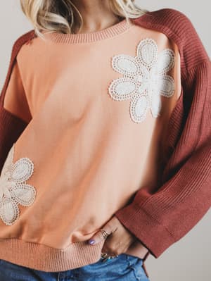 Sweater with floral lace details on a plain background