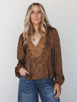 A relaxed leopard print blouse with lace-trimmed v-neckline styled with wide-leg denim — the kind of top that makes a Tuesday feel a little more intentional.