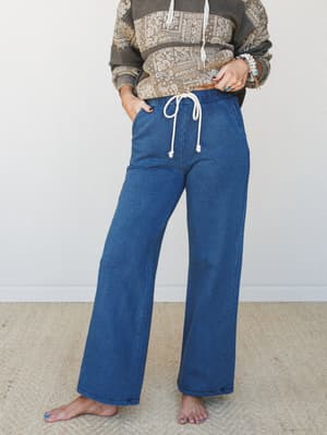Wide-leg denim-look lounge pants with a cream drawstring waist, styled with a paisley colorblock hoodie and stacked boho bracelets — the kind of outfit that looks intentional but feels like staying in.