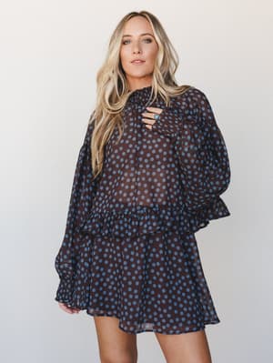 A flowy polka dot mini dress (or coordinating top and skirt set) in deep brown and dusty blue chiffon — tiered, ruffled, and sheer in all the right ways, styled with a turquoise ring for that effortless boho finish.