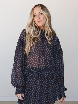 A sheer chiffon polka dot top in deep brown and dusty blue styled loosely on a model — the kind of piece that looks effortless but definitely wasn't an accident.
