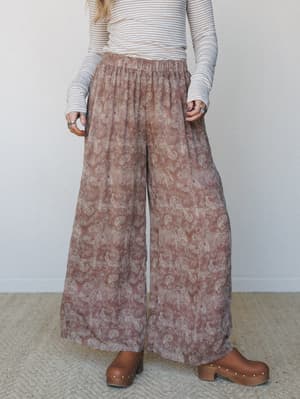 Flowy wide-leg pants in a dusty rose taupe paisley print, styled with a striped long-sleeve top and wood platform clogs — the kind of effortless, put-together look that feels equally at home at a farmers market or a long lunch.