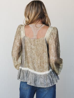Shot from the back, this flowy floral blouse layers mustard olive and dusty blue-grey panels with a delicate lace back detail and ruffled hem — the kind of top that does all the work while feeling like you're wearing nothing.
