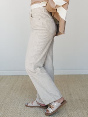 A side-profile shot focused on wide-leg corduroy pants in a soft khaki tone, styled with a color-blocked top and buckle sandals — the kind of easy, put-together look that works as hard as you do on a Saturday.