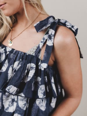 Navy blue floral dress with ruffled straps worn by a person.