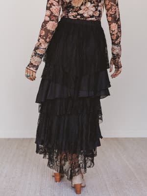 Person wearing a floral top and black lace skirt on a plain background