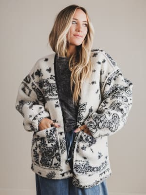 Woman wearing a patterned cardigan against a plain background