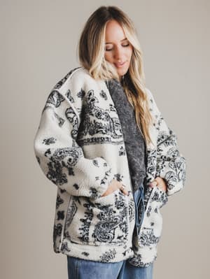 Woman wearing a patterned cardigan with a neutral background