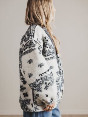 Person wearing a patterned cardigan with a neutral background