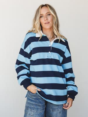 A relaxed, lived-in rugby top in bold navy and sky blue stripes styled with wide-leg denim — the kind of top that looks like it was borrowed from someone cooler than you and kept forever.