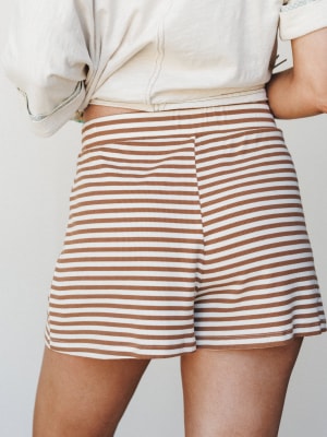 A close-up back view of ribbed stripe shorts in ivory and camel, paired with a knotted cream tee — easy, warm-toned, and made for a slow Saturday.