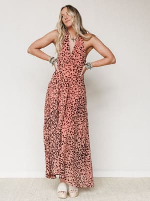 A flowy leopard-print halter maxi dress in dusty rose and brown styled with platform espadrilles and stacked bead bracelets — the kind of dress that makes you stand a little taller without trying.