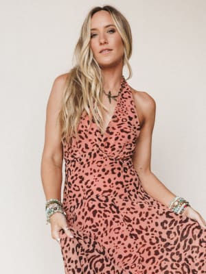 A breezy halter dress in a warm dusty rose leopard print, styled with stacked beaded bracelets and a delicate pendant necklace — the kind of outfit that makes a Tuesday feel like a vacation.