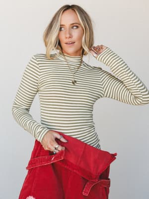 A fitted olive and cream striped mock-neck long-sleeve top styled with red corduroy bottoms — the kind of effortless color combo that looks like you planned it but swear you didn't.