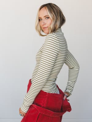 A striped olive and cream turtleneck top paired with red corduroy pants — the kind of effortless color combo that looks like you planned it but swear you didn't.