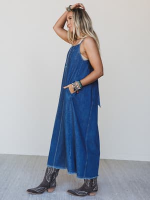 Woman wearing a blue denim dress with cowboy boots against a white background