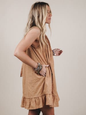 Woman wearing a tan dress against a plain background
