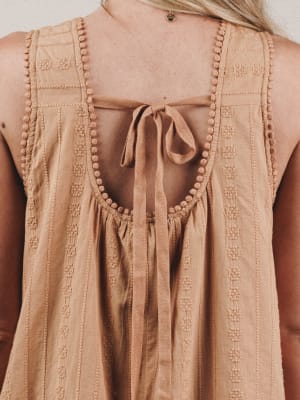 Close-up of a beige sleeveless top with intricate detailing.
