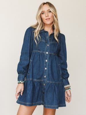A tiered denim mini dress with a babydoll silhouette, styled with stacked turquoise and beaded bracelets — the kind of piece that pulls a whole casual-cool outfit together without trying too hard.