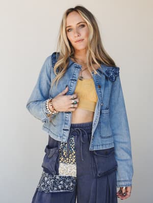 A relaxed, expressive layered look built around a light wash denim jacket with embroidered collar detail, styled over a golden yellow lace bralette and wide-leg patchwork pants — the kind of outfit that looks effortless but was definitely thought abo