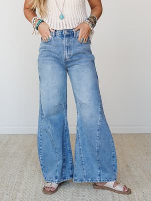 Wide-leg barrel jeans in a light drift blue wash, styled with a cream crochet tank, stacked turquoise and beaded bracelets, and white sandals — very much the outfit you wear when you want to feel put-together without trying too hard.