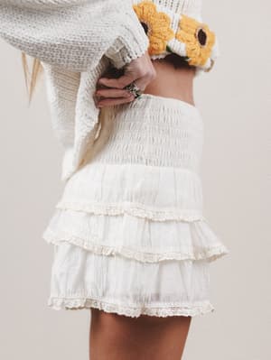 Person wearing a white lace skirt with a neutral background