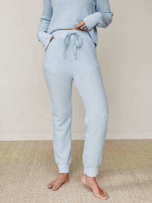 A soft waffle-knit jogger and matching top set in pale sky blue, styled barefoot with silver and turquoise rings — the kind of outfit that makes staying home feel intentional.