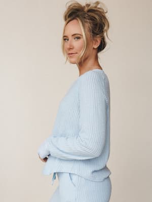 A soft, dreamy matching set in powder blue — the kind of outfit that makes staying in feel like a whole moment, shot in profile against a warm neutral backdrop.