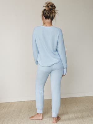 Shot from behind, a model in a matching waffle-knit set in soft powder blue — the kind of outfit that makes staying in feel intentional.