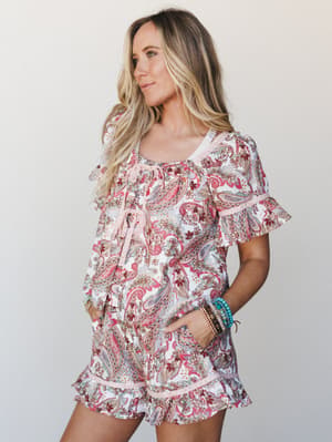 A breezy paisley matching set — flowy top and ruffle-hem shorts — styled with stacked turquoise and gold bracelets, giving off that effortless summer energy that looks intentional without trying too hard.