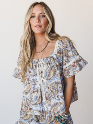 A breezy paisley set in powder blue shot against a clean studio backdrop — the flutter sleeves and lace tie front give it that effortless, just-threw-it-on feeling that somehow looks completely intentional.