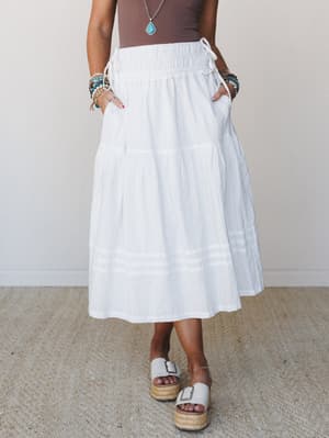 A breezy off-white tiered midi skirt styled with a chocolate bodysuit, stacked boho bracelets, a turquoise pendant necklace, and platform espadrille sandals — the kind of outfit that looks effortless but was definitely thought about.