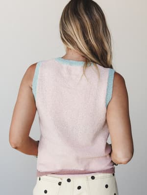 A back-view shot of a soft knit tank in blush pink with contrast mint trim at the neckline and armholes, paired with cream polka dot pants — sweet, vintage-leaning, and quietly playful.
