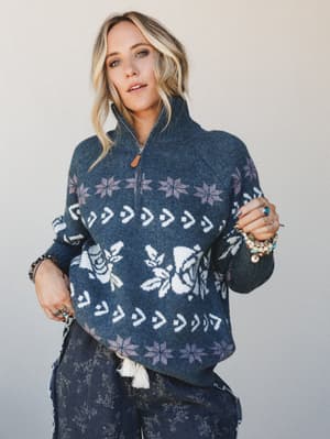A cozy Fair Isle pullover in deep indigo gets layered with stacked bracelets and printed wide-leg pants — the kind of outfit that looks like it came together effortlessly but absolutely did not.