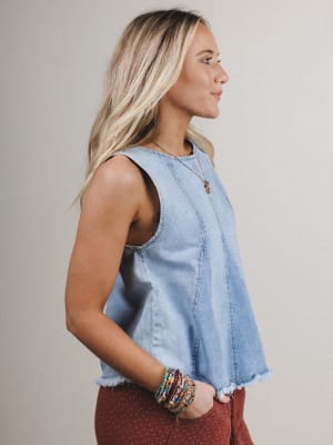 Woman wearing a denim top and red pants with a neutral background