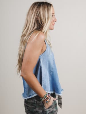 Woman wearing a light blue denim top and camouflage pants against a plain background