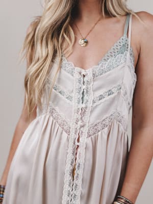 Close-up of a person wearing a white lace-trimmed dress with a neutral background