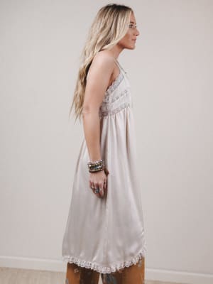 Woman wearing a light-colored dress with lace details against a plain background