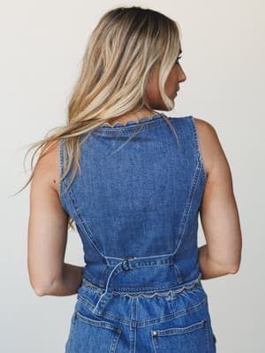 A back-facing shot of a denim sleeveless top with sweet scalloped trim details at the neckline and waist — the kind of piece that looks effortless but has just enough going on to make it interesting.