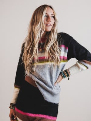 Woman wearing a colorful sweater with a neutral background