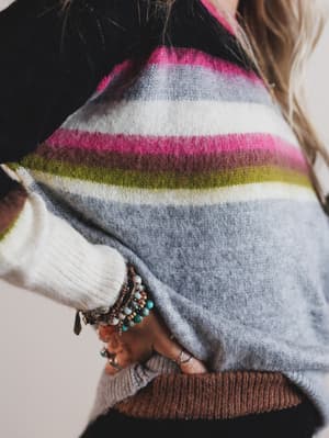 Close-up of a person wearing a colorful striped sweater with a neutral background