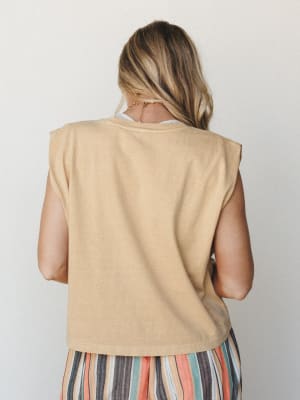 A back-view shot of a sandy, washed-out muscle tank layered over a white top, paired with a multicolor striped skirt — relaxed and easy, the kind of outfit that looks just as good at a farmers market as it does on a beach boardwalk.