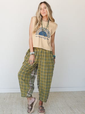 A breezy, lived-in outfit anchored by a cropped graphic muscle tank and oversized plaid barrel-leg pants, styled with layered turquoise jewelry and platform sandals for an effortlessly earthy, free-spirited look.