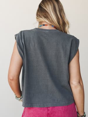 A back-view shot of a washed charcoal muscle tank with cap sleeves, styled with bright magenta bottoms and layered beaded jewelry — effortless and a little lived-in, like your favorite weekend top.