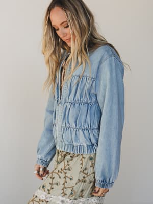 Woman wearing a light blue denim jacket against a plain background