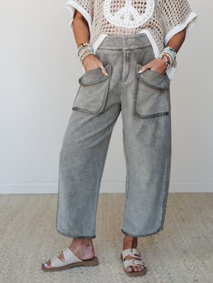 Wide-leg barrel pants in a washed olive tone styled with a crochet peace-sign top and footbed sandals — relaxed, lived-in, and effortlessly put-together from the waist down.